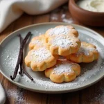 Biscuits cuillère parfumés à la vanille disposés sur une assiette en céramique vintage avec une gousse de vanille