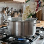 Chou-fleur surgelé versé dans une casserole d'eau bouillante sur une gazinière moderne