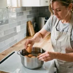 Femme plaçant des œufs entiers dans une casserole d'eau froide sur une cuisinière moderne pour une cuisson parfaite