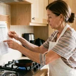 Femme consultant un tableau de conversion de température thermostat en cuisine moderne